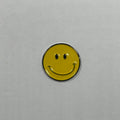 Yellow smiley face metal sticker on a gray background