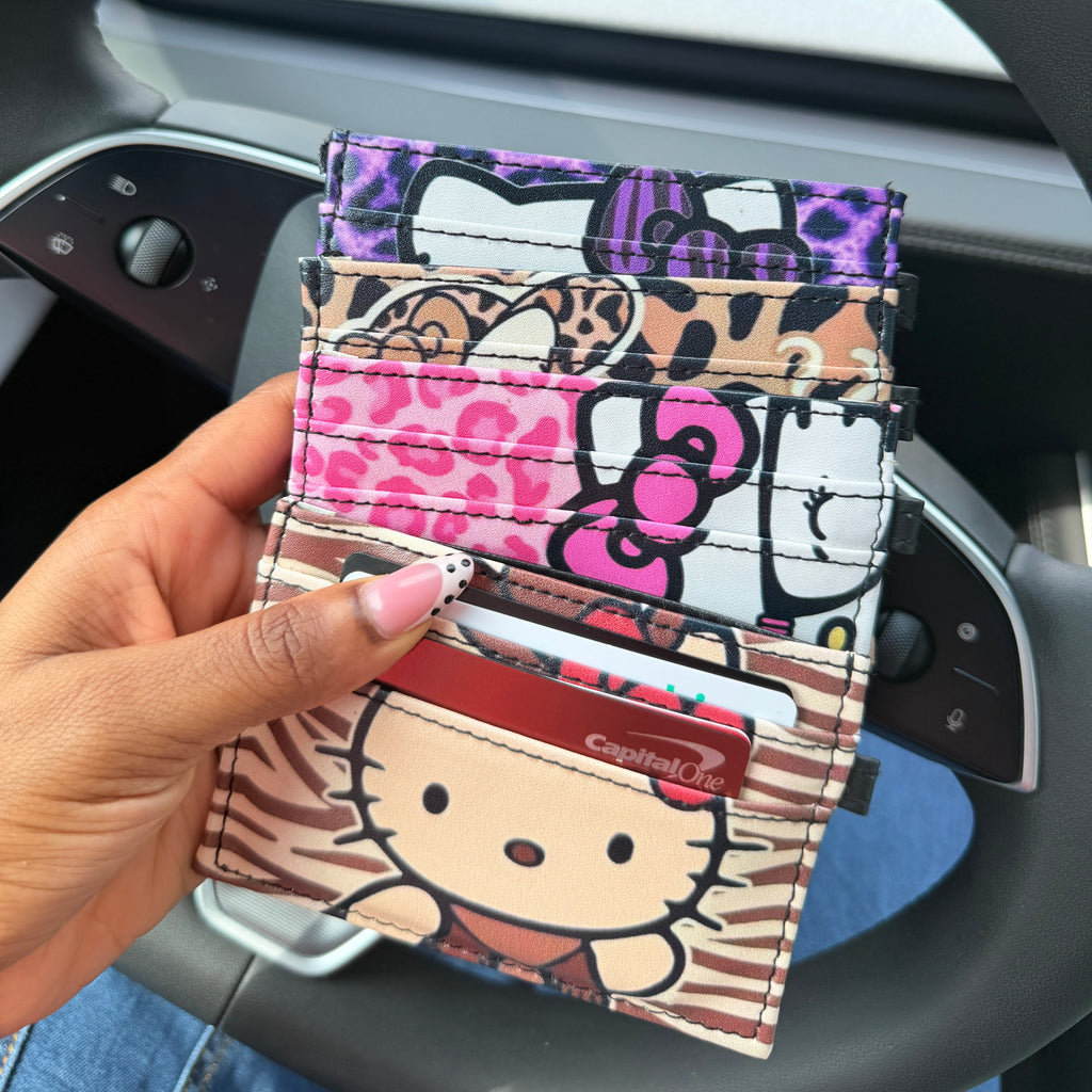 Hand holding a colorful cardholder with cartoon designs in front of a steering wheel.